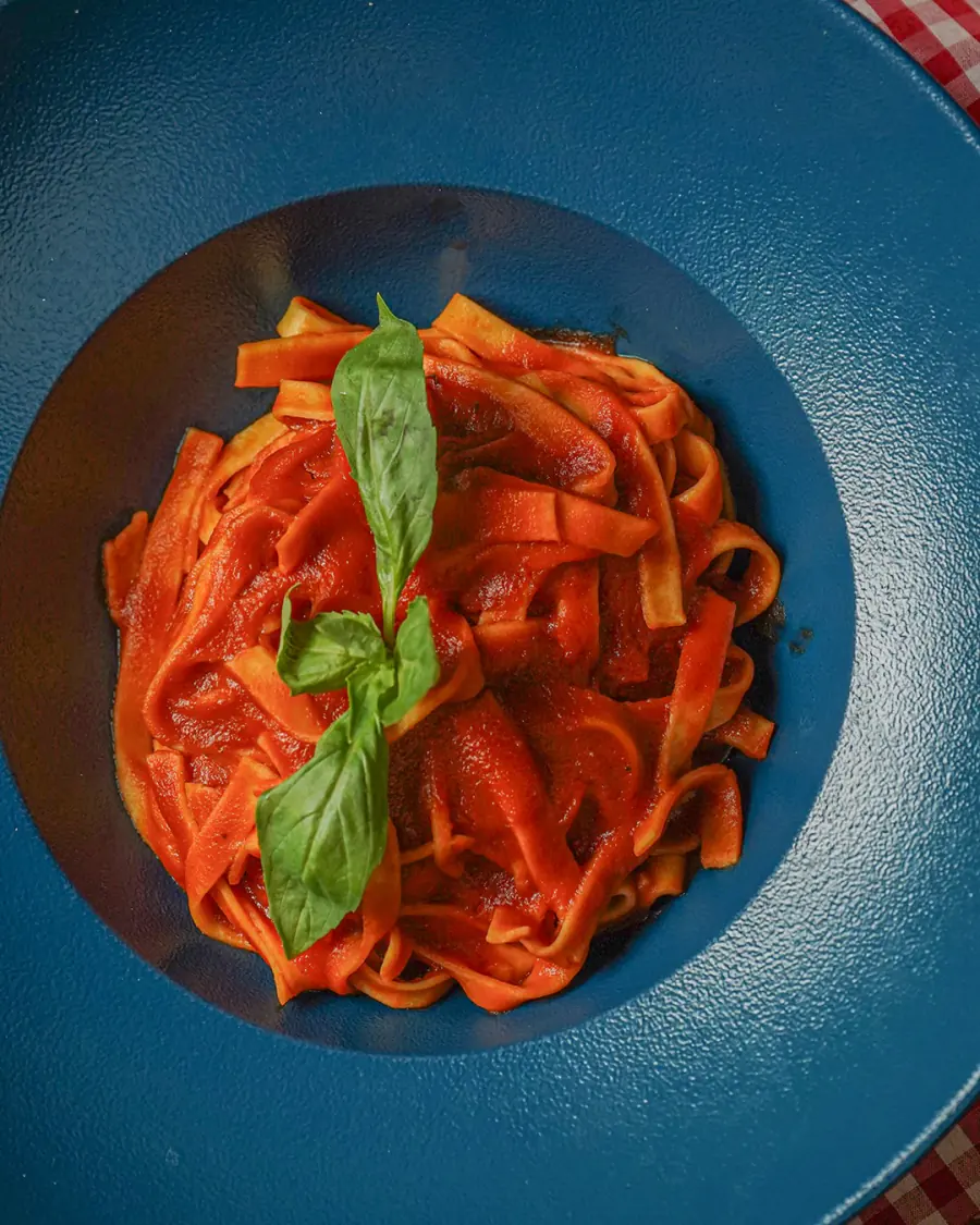 Pasta con salsa pomodoro y albahaca fresca en un plato azul