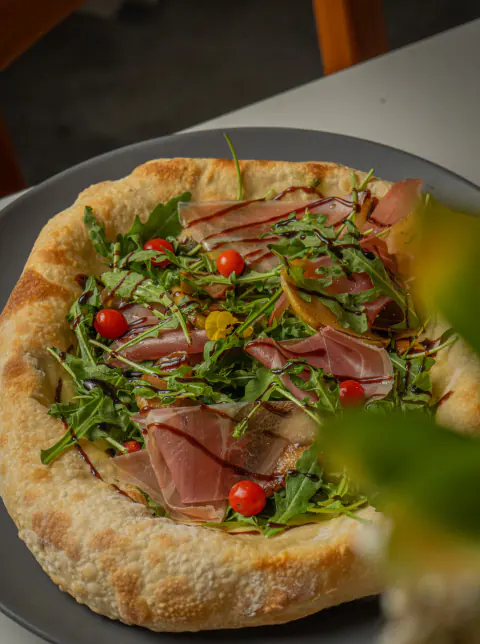 Pizza con prosciutto, rúgula y tomates cherry